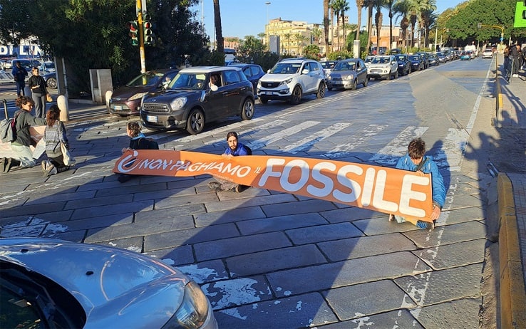 Prima protesta di Ultima generazione in Sardegna. Gli attivisti stanno bloccando la principale strada di Cagliari, via Roma lato porto, fermando tutto il traffico del centro cittadino. Cinque giovani hanno srotolato due striscioni con la scritta "Non paghiamo il fossile" e stendendosi a terra. Momenti di tensione con gli automobilisti, 13 novembre 2023. ANSA/FABRIZIO FOIS