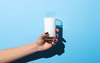 Woman holding glass of milk on blue background.Studio shot