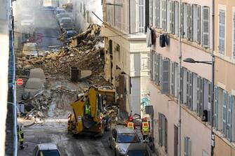 Firefighters stand next to a truck moving rubbles where a building collapsed in Marseille, southern France, on April 9, 2023. - "We have to be prepared to have victims," the mayor of Marseille warned on April 9, 2023 after a four-storey apartment building collapsed in the centre of France's second city, injuring five people, according to a provisional report. (Photo by NICOLAS TUCAT / AFP) (Photo by NICOLAS TUCAT/AFP via Getty Images)