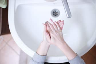 Una donna si lava e si asciuga le mani al lavandino con il sapone