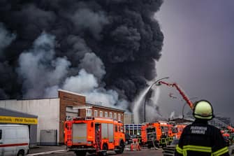 epa10566214 Firefighters try to extinguish a fire burning at a warehouse in the Rothenburgsort district of Hamburg, Germany, 09 April 2023. Residents have been warned of heavy smoke and possible toxins in the air. An alert issued by the Hamburg fire department said smoke gasses and chemical components in the air could affect breathing.  EPA/DOMINICK WALDECK