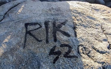 Una scritta nera, forse una
firma con la bomboletta spray, su una roccia di granito davanti
al mare azzurro di Villasimius, lungo la costa sud orientale
della Sardegna, 25 Agosto 2023. ANSA/US GUARDIE AMBIENTALI SARDEGNA