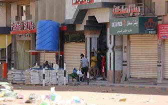 epa10579978 Sudanese people stand in front of a shop in Khartoum, Sudan, 19 April 2023. A power struggle erupted since 15 April between the Sudanese army led by army Chief General Abdel Fattah al-Burhan and the paramilitaries of the Rapid Support Forces (RSF) led by General Mohamed Hamdan Dagalo, resulting in at least 200 deaths according to doctors' association in Sudan.  EPA/STRINGER