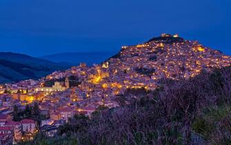 View of the town of Agira, situated on a hill, illuminated at night.