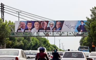 Vehicles move past a billboard displaying the faces of the six candidates running in the upcoming Iranian presidential election in the Iranian capital Tehran on June 16, 2024. (Photo by ATTA KENARE / AFP) (Photo by ATTA KENARE/AFP via Getty Images)