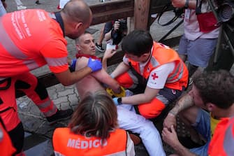 First responders tend to an injured participant after the "encierro" (bull-run) of the San Fermin festival in Pamplona, northern Spain, on July 9, 2023. Thousands of people every year attend the week-long festival and its famous 'encierros': six bulls are released at 8:00 a.m. evey day to run from their corral to the bullring through the narrow streets of the old town over an 850 meters (yard) course while runners ahead of them try to stay close to the bulls without falling over or being gored. (Photo by CESAR MANSO / AFP) (Photo by CESAR MANSO/AFP via Getty Images)
