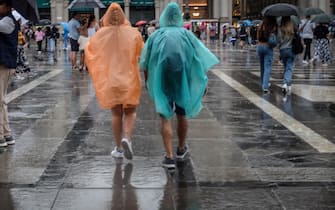 Persone si riparano con gli ombrelli dalla pioggia nel centro di Milano, 18 agosto 2022. ANSA/MATTEO CORNER