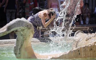 Una donna si rinfresca in una fontana