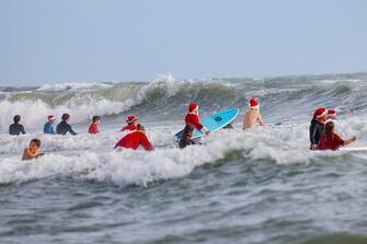 Surfers dressed as Santa go into the water to ride waves during the 15th annual "Surfing Santas" event in Cocoa Beach, Florida, on December 24, 2023. (Photo by Eva Marie UZCATEGUI / AFP) (Photo by EVA MARIE UZCATEGUI/AFP via Getty Images)