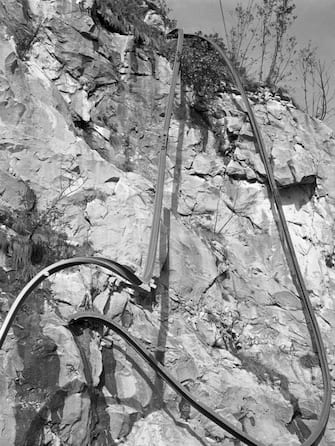 A crooked rail hangs down a cliff, Longarone, near the Vajont Dam in the Piave Valley, Italy, early October, 1963. On October 9, a landslide in the dam basin caused a wave more than 800 feet high to overtop the dam and flood the valley below--five villages were completely destroyed, more than 2000 people were killed, and thousands more were left homeless and displaced. (Photo by Archivio Cameraphoto Epoche/Getty Images)