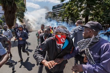 Protesters retreat from a cloud of tear gas during a nationwide strike to protest against tax hikes and the Finance Bill 2024 in downtown Nairobi, on June 25, 2024. Kenyan police shot dead one protester near the country's parliament Tuesday, a rights watchdog said as demonstrators angry over proposed tax hikes breached barricades and entered the government complex, where a fire erupted. The mainly Gen-Z-led rallies, which began last week, have taken President William Ruto's government by surprise, with the Kenyan leader saying over the weekend that he was ready to speak to the protesters. (Photo by Tony KARUMBA / AFP) (Photo by TONY KARUMBA/AFP via Getty Images)