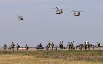 Boeing CH-47F Chinook tandem rotor helicopters (Vertol) and military personnel of the US Army's 101st Airborne Division perform during a demonstration drill at Mihail Kogalniceanu Airbase near Constanta, Romania on July 30, 2022. Members of the 101st Airborne Division (Air Assault) headquarters and its 2nd Brigade Combat Team in a ceremony marked their official arrival in Europe at the airbase. The ceremony was followed by a 'Romania/US Air and Land Showcase', a combined US Army and Romanian Army capabilities demonstration. (Photo by Daniel MIHAILESCU / AFP) (Photo by DANIEL MIHAILESCU/AFP via Getty Images)