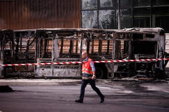 epa10718757 An RATP employee walks past charred buses that were burned overnight at a public transport site in Aubervilliers, near Paris, France, 30 June 2023. Violence broke out all over France after police fatally shot Nael, a 17-year-old, during a traffic stop in Nanterre on 27 June.  EPA/YOAN VALAT