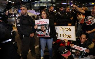 Israeli security forces stand guard as relatives and supporters hold placards bearing portraits of Israeli hostages held in Gaza since the October 7 attacks by Hamas in southern Israel, during a rally calling for their release, in Tel Aviv on January 20, 2023. The placards (C) show Matan Zangauker. (Photo by AHMAD GHARABLI / AFP)