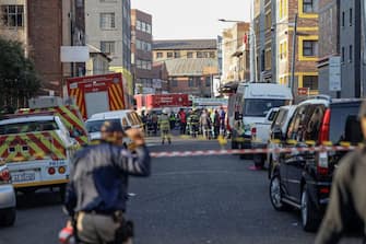 South African firefighters and South African Police Service officers work at the sceen of a fire in Johannesburg on August 31, 2023. At least 20 people have died and more than 40 were injured in a fire that engulfed a five-storey building in central Johannesburg on August 31, 2023, the South African city's emergency services said. (Photo by Michele Spatari / AFP) (Photo by MICHELE SPATARI/AFP via Getty Images)