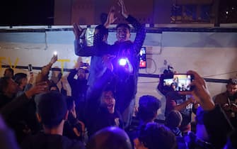 People celebrate while watching a television along a street in Khan Yunis in the southern Gaza Strip on January 15, 2025, amid the ongoing war in the Palestinian territory between Israel and Hamas. Thousands of Gazans celebrated on January 15 as news spread that a ceasefire and hostage release deal had been reached between Israel and Hamas, aimed at ending more than 15 months of war in the Palestinian territory. (Photo by BASHAR TALEB / AFP)