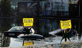 epa10839229 Greenpeace protesters stand in a lake hold placards stating 'Auto industry sinks climate protection' in front of the venue of the International Motor Show (IAA) in Munich, Germany, 04 September 2023. The 2023 International Motor Show Germany IAA MOBILITY 2023 takes place in Munich from 05 to 10 September 2023. IAA 2023 will also feature numerous world premieres and has a special focus on electric mobility and digitization.  EPA/RONALD WITTEK