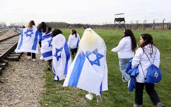 epa10578588 People wearing Israeli flags walk along the tracks during the  March of the Living  along the 'road of death' from the former Nazi German Auschwitz I camp to Auschwitz II-Birkenau in Oswiecim, Poland, 18 April 2023. The annual march, commemorating the victims of the Holocaust, takes place annually since 1988 at the site of Nazi German concentration and extermination camp Auschwitz-Birkenau. Over 1.1 million people, mostly Jews, lost their lives in Auschwitz death camps during the World War II.  EPA/ZBIGNIEW MEISSNER POLAND OUT