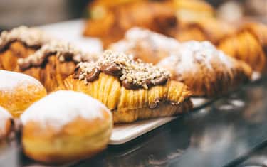 Fresh hot and gold French bakery on trays, crusty and sweet vegan treats. Homemade flaky pastry dough croissants, moist donuts, and buns with various flavored fillings. Breakfast or brunch ideas for a Sunday morning