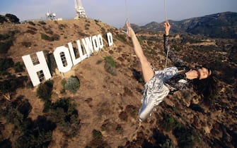 HOLLWOOD, CA - JUNE 1998: Michelle Yeoh in mid-air over the famous Hollywood sign in the afternoon in November of 1998. Michelle Yeoh, born in Malaysia, is now an internationally known "action goddess," having starred in the stunning film "Crouching Tiger, Hidden Dragon," in which characters fly during action sequences. The film spawned a new Asian action genre replete with aerial sequences created with contemporary special effects.(Photo by Joe McNally/Getty Images)