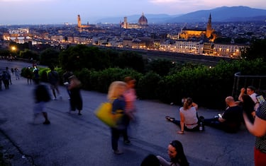 Tourists enjoy the view from Piazzale Michelangelo (Michelangelo Square) at sunset on May 26, 2018, with the Arno River, the Florence Cathedral, formally called Cattedrale di Santa Maria del Fiore (C), Florence's townhall Palazzo Vecchio (L) and The Basilica di Santa Croce (R), in Florence. (Photo by ANDREAS SOLARO / AFP)        (Photo credit should read ANDREAS SOLARO/AFP via Getty Images)