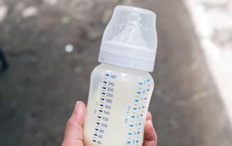 Hand holding baby milk bottle.  Personal perspective. Copy space. Selective focus.