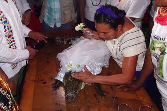 Villagers bless a spectacled caiman (Caiman crocodilus) called "La NiÃ±a Princesa" ("The Princess Girl"), dressed as a bride, before being married to the Mayor in San Pedro Huamelula, Oaxaca state, Mexico on June 30, 2023. This ancient ritual of more than 230 years unites two ethnic groups in marriage to bring prosperity and peace. The spectacled caiman (Caiman crocodilus) is paraded around the community before being dressed as a bride and marrying the Mayor. According to beliefs, this union between the human and the divine will bring blessings such as a good harvest and abundant fishing. (Photo by RUSVEL RASGADO / AFP) (Photo by RUSVEL RASGADO/AFP via Getty Images)