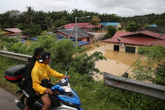 epa10501879 People look at a flooded residential area in Yong Peng, Johor, Malaysia, 04 March 2023. According to state media, more than 33,000 people were evacuated in four states affected by the floods.  EPA/FAZRY ISMAIL