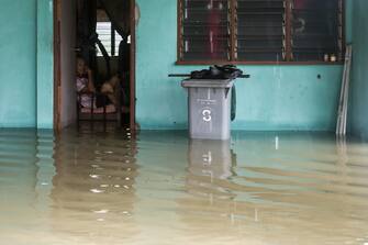 epa10501689 A man (L) looks at flood waters outside his house after some areas in Johor state were affected by flooding, in Yong Peng, Johor, Malaysia, 04 March 2023. According to state media, more than 33,000 people were evacuated in four states affected by the flooding.  EPA/FAZRY ISMAIL