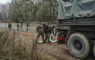 Polish Army soldiers unload razor wire from a military truck while constructing a fence along the Polish border, with the Russian enclave of Kaliningrad, near Zerdziny, Poland, on Saturday, Nov. 5, 2022. The Baltic region of Kaliningrad, cut off from the rest of Russia after the independence of the Baltic states in 1990, was in German hands for centuries until it was seized and annexed by the Soviet Union in 1945. Photographer: Damian Lemankski/Bloomberg