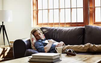 Mid adult man with digital tablet sleeping on sofa at home