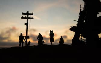 Refugees and captive walking in destroyed city. Terrible face of war concept. Creative artwork table decoration with light and fog. Selective focus.