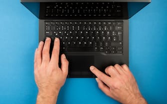 directly above view of man using laptop computer on blue desk background