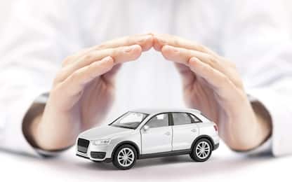 Car insurance. Small silver toy car covered by hands
