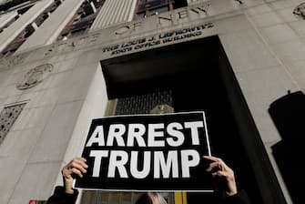 epa10534361 A protester holds up sign outside the New York State Louis Lefkowitz office building where grant jury testimony is being heard in the possible indictment of Former President Donald Trump, in New York, New York, USA, 20 March 2023. Former President Donald J. Trump posted on his social media platform that he expects to be formally indicted on 21 March, the Manhattan District Attorney investigating charges related to hush-money payments to porn star Stormy Daniels have declined to comment on any potential indictment.  EPA/Peter Foley