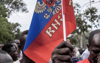 A demonstrator holds a Russian flag with the emblem of Russia on in Bangui, on March 22, 2023 during a march in support of Russia and China's presence in the Central African Republic. - Central African Republic authorities have opened an investigation into the deaths of nine Chinese nationals killed in an attack on a gold mine in the centre of the country on March 19, 2023. Taking advantage of the vacuum created by the departure of the bulk of French troops, Moscow sent "military instructors" to the country in 2018, then hundreds of Wagner paramilitaries in 2020 at the request of Bangui, faced with a threatening rebellion. (Photo by Barbara DEBOUT / AFP) (Photo by BARBARA DEBOUT/AFP via Getty Images)