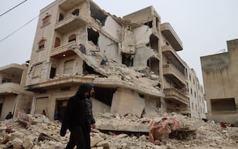 Two men walk past a heavily damaged building following an earthquake in the town of Sarmada in the countryside of the northwestern Syrian Idlib province, early on February 6, 2023. - A 7.8-magnitude earthquake hit Turkey and Syria on February 6, killing hundreds of people as they slept, levelling buildings, and sending tremors that were felt as far away as the island of Cyprus and Egypt. (Photo by Mohammed AL-RIFAI / AFP) / The erroneous mention[s] appearing in the metadata of this photo by Mohammed AL-RIFAI has been modified in AFP systems in the following manner: [the town Sarmada] instead of [Zardana]. Please immediately remove the erroneous mention[s] from all your online services and delete it (them) from your servers. If you have been authorized by AFP to distribute it (them) to third parties, please ensure that the same actions are carried out by them. Failure to promptly comply with these instructions will entail liability on your part for any continued or post notification usage. Therefore we thank you very much for all your attention and prompt action. We are sorry for the inconvenience this notification may cause and remain at your disposal for any further information you may require. (Photo by MOHAMMED AL-RIFAI/AFP via Getty Images)