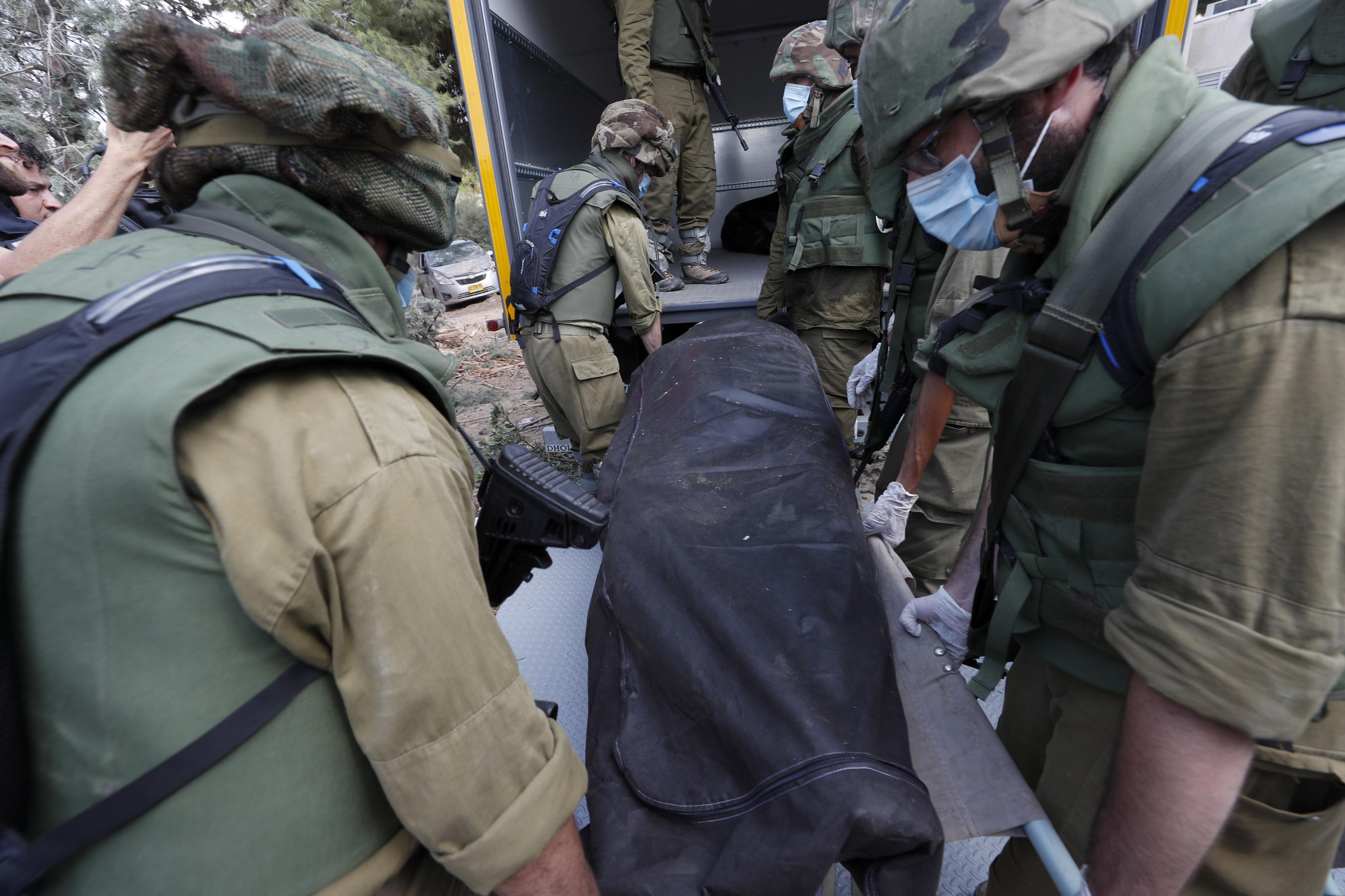 epa10911385 Israeli soldiers take the bodies of Israelis killed in Kfar Aza kibbutz near the border with Gaza, 10 October 2023. More than 900 people have been killed, around 150 were taken as hostages, and 1,500 others injured, according to Israel Defence Forces (IDF), after the Islamist movement Hamas launched an attack against Israel on 07 October. More than 3,000 people, including 1,500 militants from Hamas, have been killed and thousands injured in Gaza and Israel since 07 October, according to Israeli military sources and Palestinian officials.  EPA/ATEF SAFADI