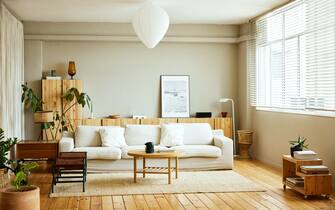 Sofa with coffee table by window in living room. Picture frame is on cabinet at home. Interior of modern bright apartment.