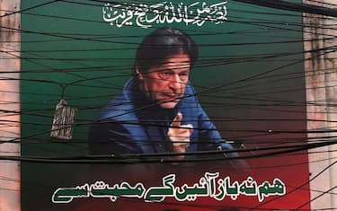 A poster of Pakistan's ex-prime minister Imran Khan is seen through cables in Lahore on December 18, 2023. Artificial intelligence allowed Khan to campaign from behind bars on December 18, with a voice clone of the opposition leader giving an impassioned speech on his behalf. (Photo by Arif ALI / AFP)