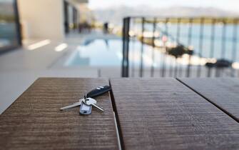 House keys on wooden table against swimming pool