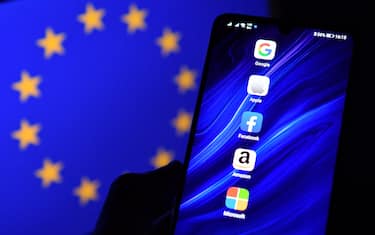 An illustration picture taken in London on December 18, 2020 shows the logos of Google, Apple, Facebook, Amazon and Microsoft displayed on a mobile phone with an EU flag displayed in the background. (Photo by JUSTIN TALLIS / AFP) (Photo by JUSTIN TALLIS/AFP via Getty Images)