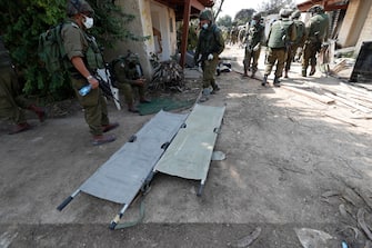 epa10911388 Israeli soldiers take the bodies of Israelis killed in Kfar Aza kibbutz near the border with Gaza, 10 October 2023. More than 900 people have been killed, around 150 were taken as hostages, and 1,500 others injured, according to Israel Defence Forces (IDF), after the Islamist movement Hamas launched an attack against Israel on 07 October. More than 3,000 people, including 1,500 militants from Hamas, have been killed and thousands injured in Gaza and Israel since 07 October, according to Israeli military sources and Palestinian officials.  EPA/ATEF SAFADI