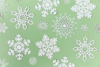 Stock photo of snowflakes made of paper collected together on top of pale green background