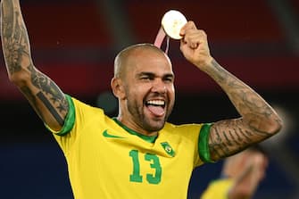 Brazil's gold medallist Dani Alves celebrates after receiving his medal on the podium during the medal ceremony of the Tokyo 2020 Olympic Games men's football competition at Yokohama International Stadium in Yokohama, Japan, on August 7, 2021. (Photo by Anne-Christine POUJOULAT / AFP) (Photo by ANNE-CHRISTINE POUJOULAT/AFP via Getty Images)