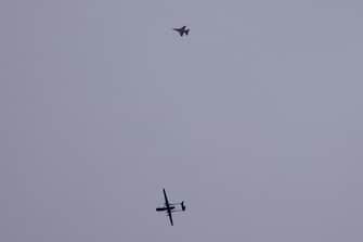 An Israeli unmanned aerial vehicle (UAV or drone) and a fighter jet (top) fly over the border with the Gaza Strip in southern Israel on November 17, 2023 amid the ongoing battles between Israel and the Palestinian group Hamas in the Gaza Strip. (Photo by JACK GUEZ / AFP)