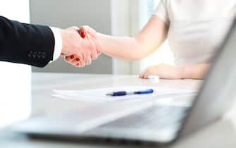 Business man and woman shaking hands after successful job interview or meeting. Young applicant making contract of employment.