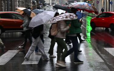 Alcune persone camminano riparandosi dalla pioggia con gli ombrelli a Genova, 8 ottobre 2024. Allagamenti diffusi sul territorio ligure. Scuole chiuse in via precauzionale in molti comuni, allerta arancione nel centro della regione, mentre nel Tigullio e nello spezzino il livello di allerta rossa per i grandi bacini dell'Entella e del Magra.(pioggia,. maltempo, simbolica, pioggia, generica) ANSA/LUCA ZENNARO