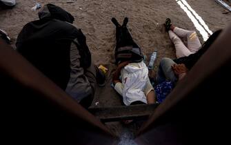 epa10620055 Migrants wait at the border wall to be brought by Border Patrol officers to a processing center along the border of Mexico and the United States, in Yuma, Arizona, USA, 10 May 2023. A significant increase in the number of migrant crossings is expected as the COVID-era Title 42 policy, which allowed for a quick expulsion of illegal immigrants, is set to expire on 11 May.  EPA/ETIENNE LAURENT