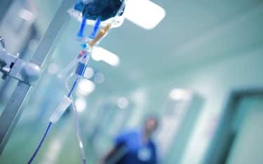Intravenous drip with blue liquid ready to use on the background of walking around medical doctor, concept of mersy killing.